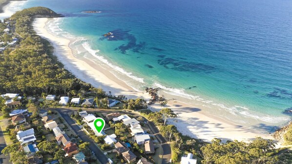 Enjoy stunning ocean views from this beachfront property, surrounded by lush greenery and expansive white sandy shores.
