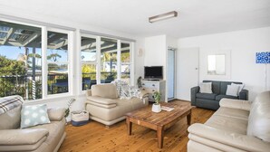 Ein geräumiges Wohnzimmer mit großen Fenstern, einem Holztisch und zwei Sofas.