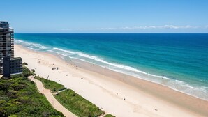 Una playa con vista despejada al océano, una orilla arenosa y un edificio de varios pisos.