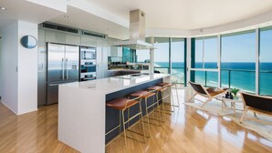 Una cocina moderna con una isla grande, taburetes de bar y vistas al océano.
