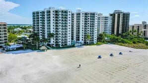 A beachfront hotel with multiple high-rise buildings, a sandy beach, and some palm trees.