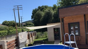 A swimming pool with a wooden deck, a small laundry room, and a wooden building with a window. - Recinto Hotelero As Casiñas (Cangas)