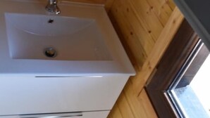 A wooden-paneled room with a white sink and a window. - Recinto Hotelero As Casiñas (Cangas)