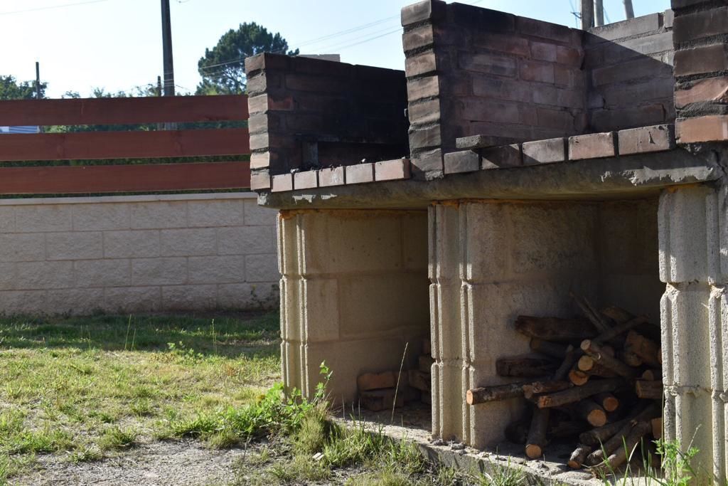 A brick structure with a partially open door, revealing a stack of firewood inside.