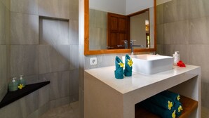 A modern bathroom with a large sink, mirror, and wooden vanity.