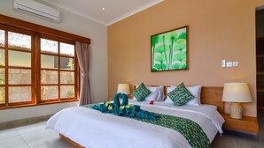 A hotel room with a large bed, a window with curtains, a painting on the wall, and a bedside lamp.
