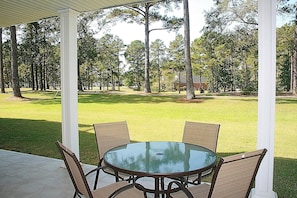 A covered patio area with a round glass table and four chairs.