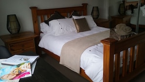 A neatly made bed with white and brown bedding, a wooden headboard, and a bedside table with a lamp. - Fully furnished 2 room apartment - sleeps 4 (Axedale)