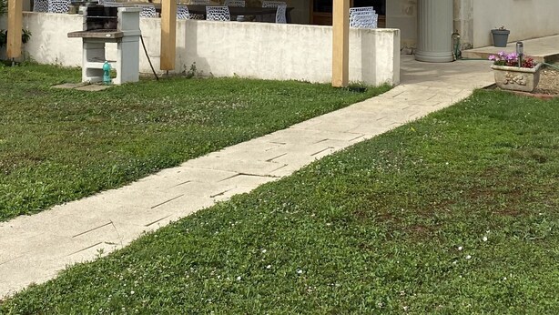 Une maison en pierre avec un toit en tuiles et un patio couvert.