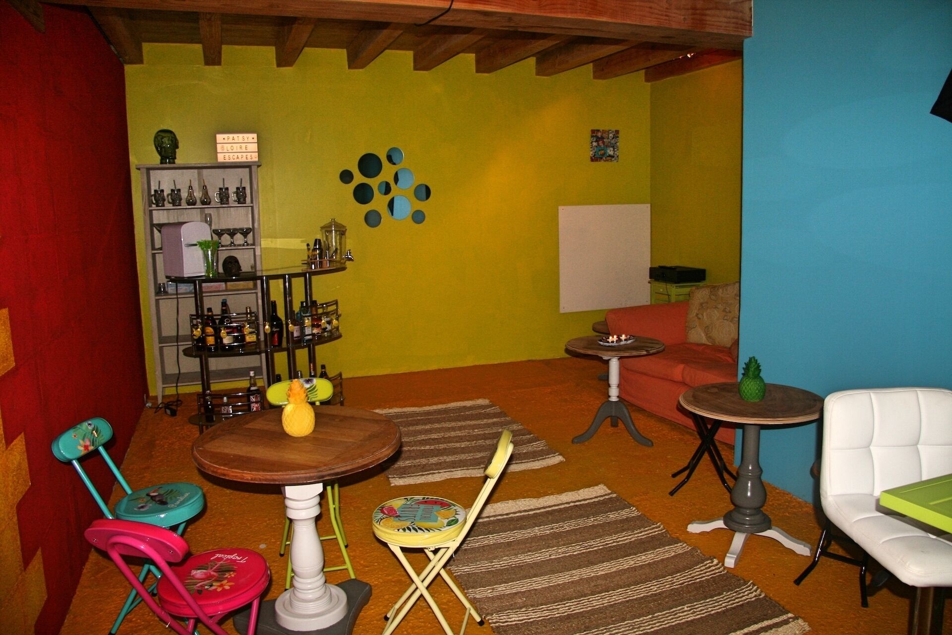 Une pièce avec un plafond en bois, une bibliothèque, une petite table ronde, une chaise blanche et un tapis coloré.
