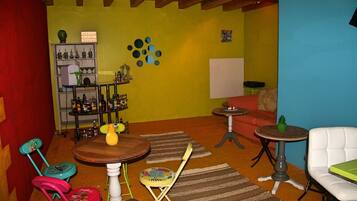 Une pièce avec un plafond en bois, une bibliothèque, une petite table ronde, une chaise blanche et un tapis coloré.