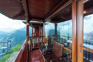 Un balcon en bois, agrĂ©mentĂ© dâune table et de chaises, qui offre une vue sur un paysage montagneux.