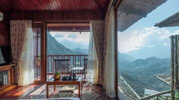 A room with a balcony, a wooden ceiling, and a view of mountains.
