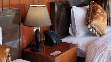 A hotel room with a wooden headboard, a bedside lamp, a telephone, and a decorative pillow.