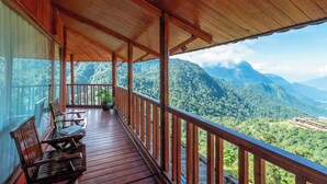 A wooden balcony with a view of a mountainous landscape.