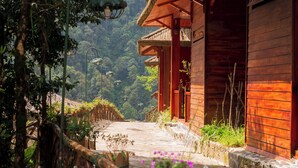 A traditional wooden building with a stone pathway leading to it, surrounded by greenery.