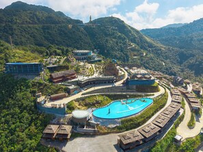 A resort with a swimming pool, traditional buildings, and a mountainous backdrop. - Heaven Gate Hotel O Quy Ho (Tam Duong)
