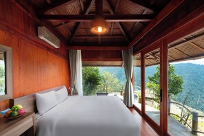 A bedroom with a wooden ceiling, a bed, a nightstand with fruit, and a view of the outdoors. - Heaven Gate Hotel O Quy Ho (Tam Duong)