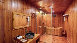 A wooden interior with a wooden bathtub, a glass-enclosed shower, and a wooden vanity with a bowl sink.