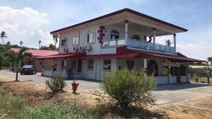 Un edificio de dos pisos con balcón, techo rojo y fachada blanca.
