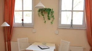 Una habitación con una mesa blanca, dos sillas, un radiador y una ventana con cortinas.