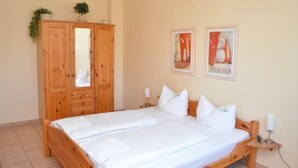 Un dormitorio con una cama de madera, un armario y dos cuadros en la pared.