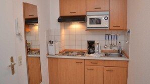 Una cocina compacta con armarios de madera, microondas, cafetera y comodidades básicas.