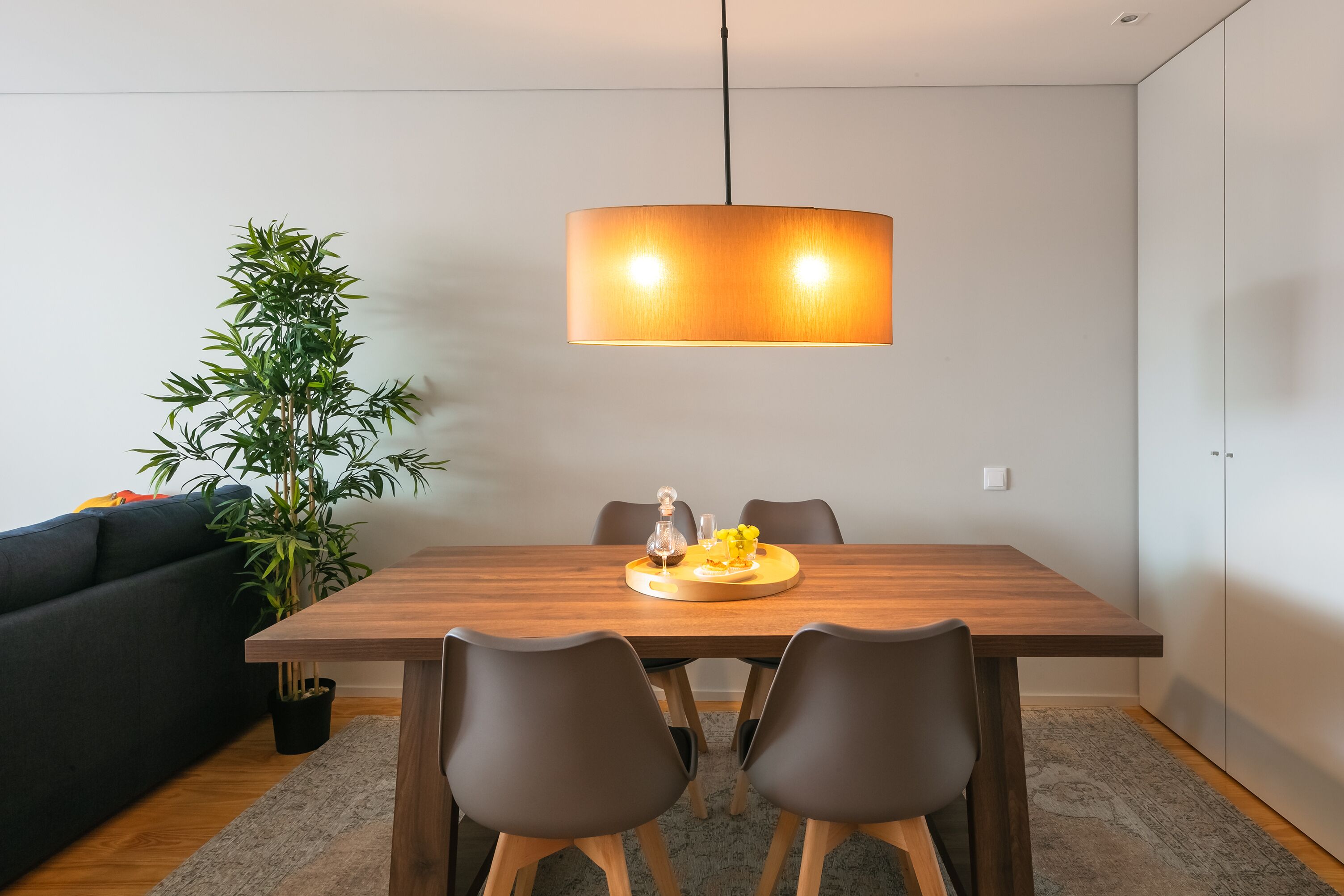 Ett modernt matområde med ett träbord, fyra stolar och en hängande lampa.