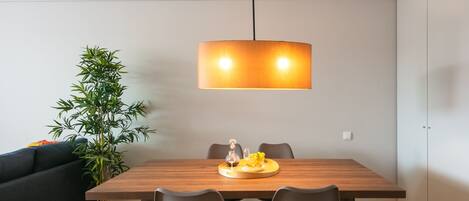 Ett modernt matområde med ett träbord, fyra stolar och en hängande lampa.