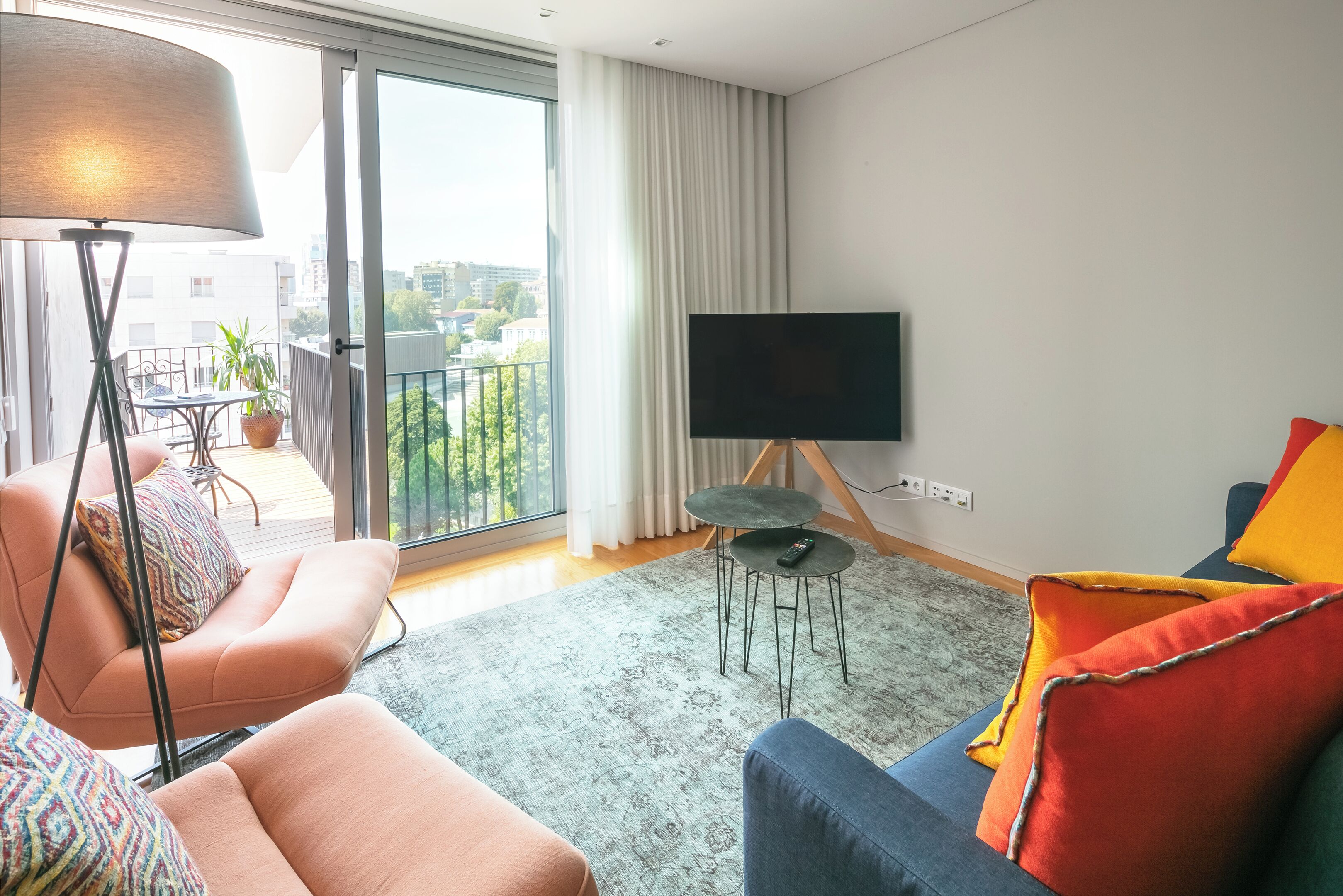 A modern living room with a sofa, armchair, and a TV on a stand.