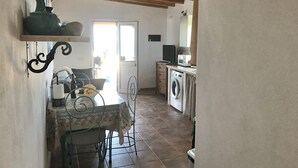 Eine Küche mit Waschmaschine, Mikrowelle und Essbereich inklusive Tisch und Stühlen.