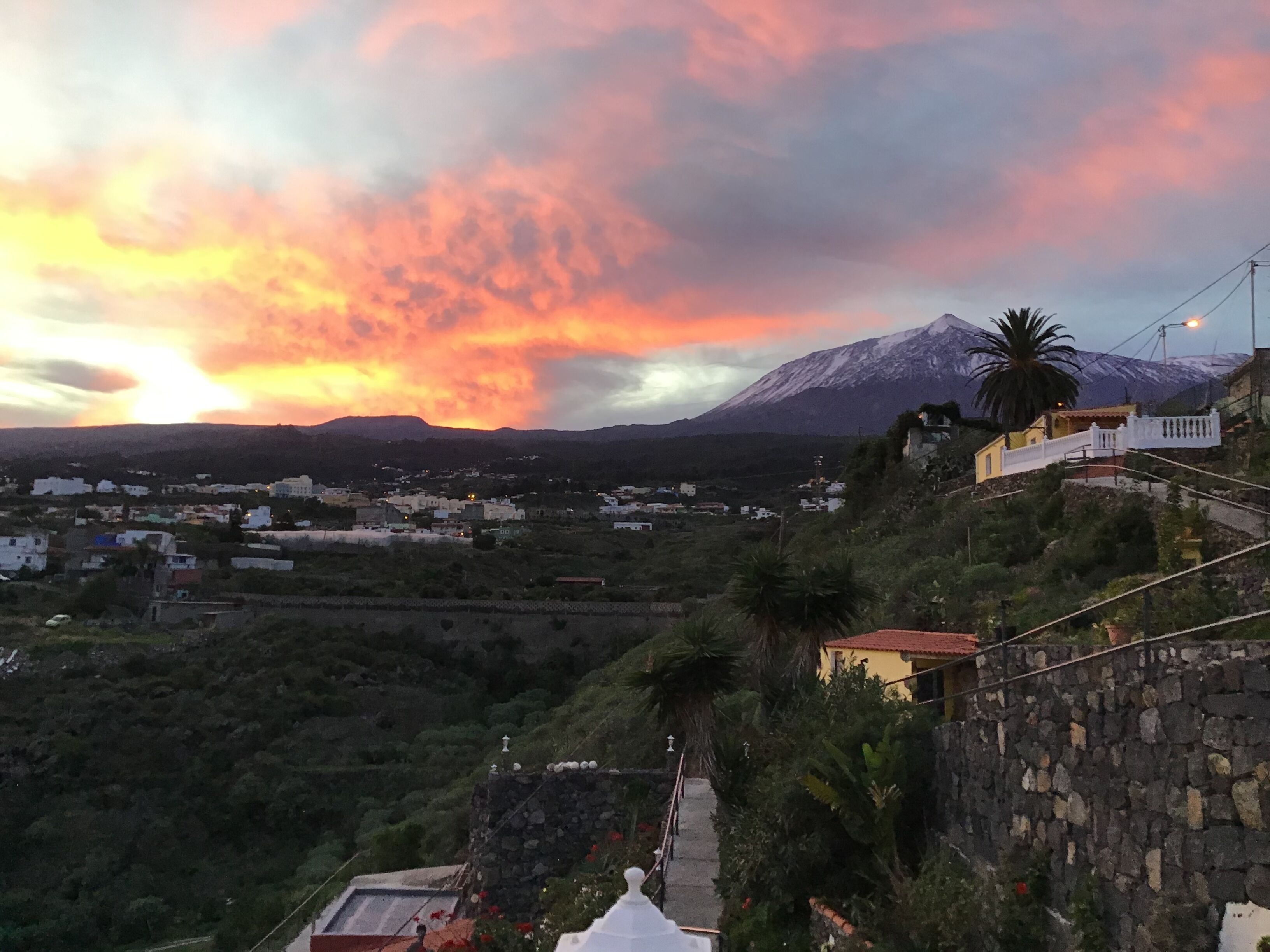 A mountainous landscape with a sunset, a village below, and a prominent mountain in the background.
