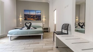 A bedroom with a bed, bedside tables, a desk, and a chair. There are wall-mounted lights and a large mirror. - Moon Bologna (Bologna)