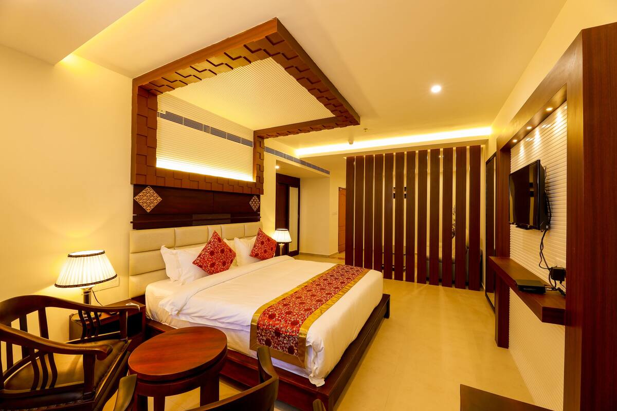 Ein Hotelzimmer mit einem großen Bett, einem Schreibtisch, einem Stuhl, einem Fernseher und einer Holzwand.