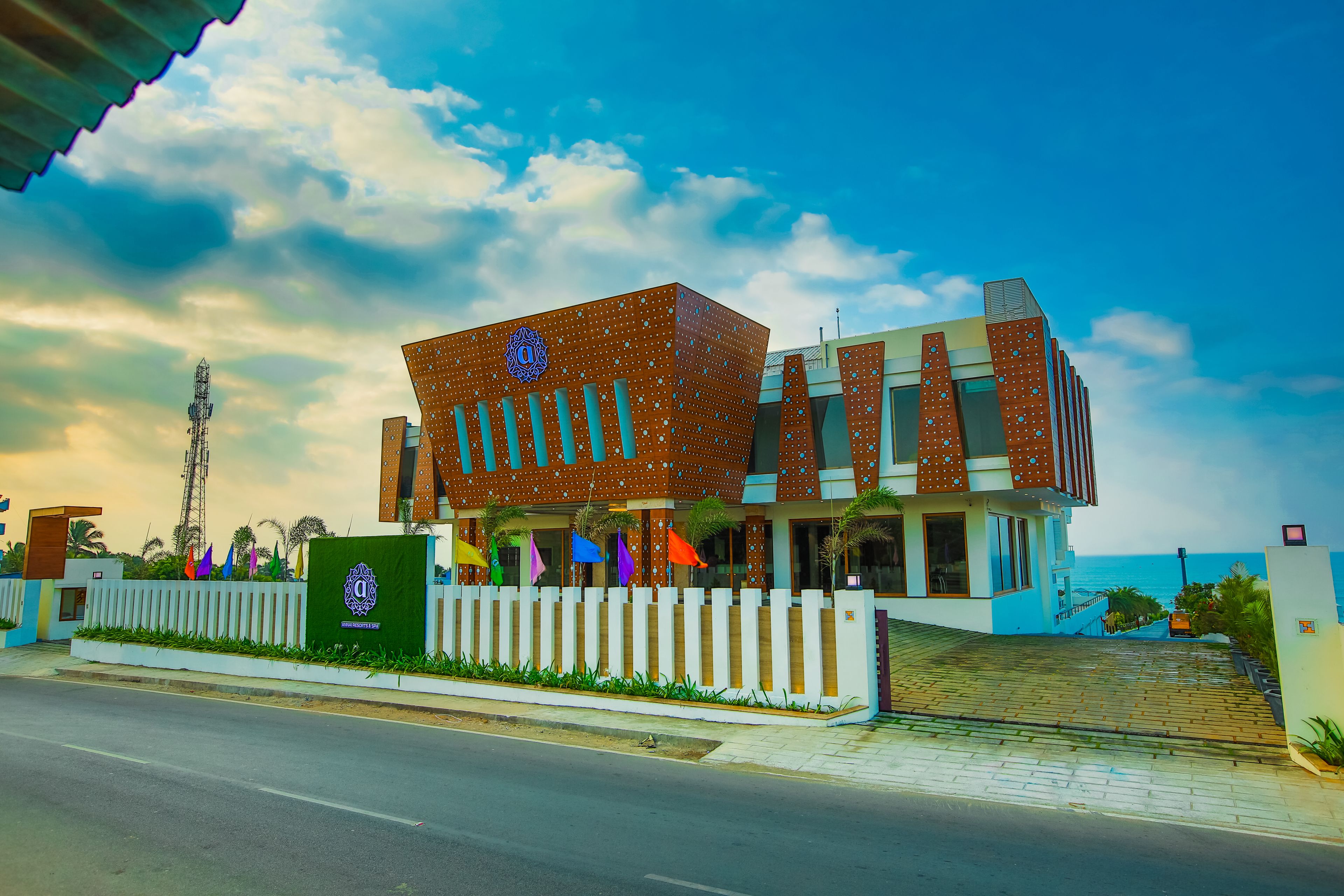 A modern building with a distinctive geometric design, a white picket fence, and a view of the ocean.