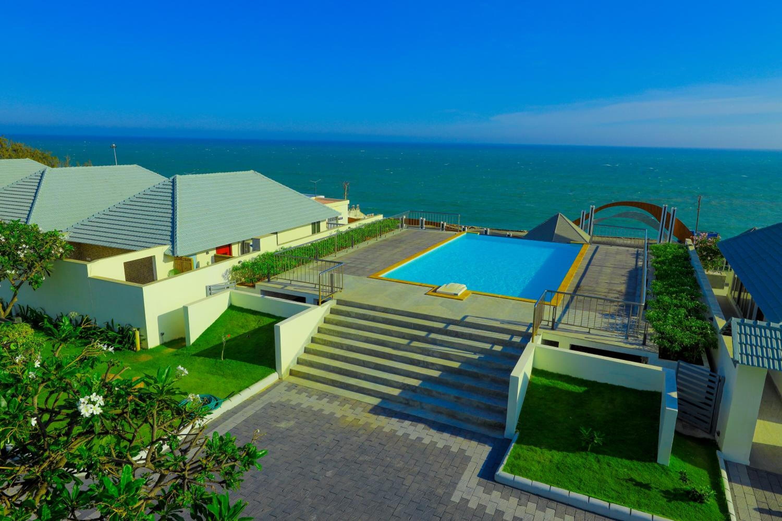 A resort with a swimming pool, a staircase leading to a deck, and a view of the ocean.