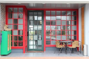 A room with a red-framed door, a green cabinet, and a table with chairs.