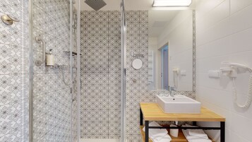A modern bathroom with a glass shower enclosure, a sink with a mirror, and a towel rack.