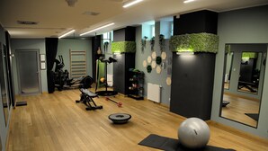 Un gimnasio con equipo de ejercicio, un espejo grande y piso de madera.