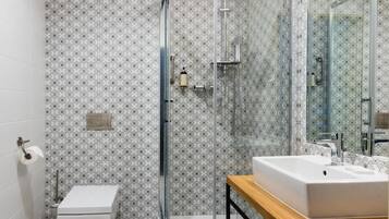 A modern bathroom with a glass-enclosed shower, a white toilet, and a wooden vanity with a sink.
