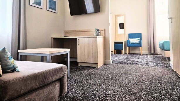 A hotel room with a bed, a desk, a TV, and a chair. - Hotel Eureka (Sopot)