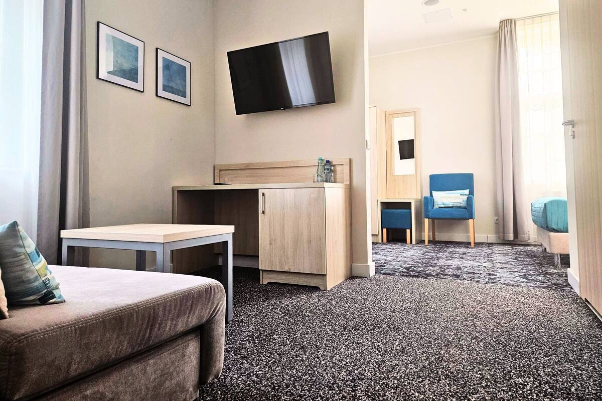 A hotel room with a bed, a desk, a TV, and a chair.