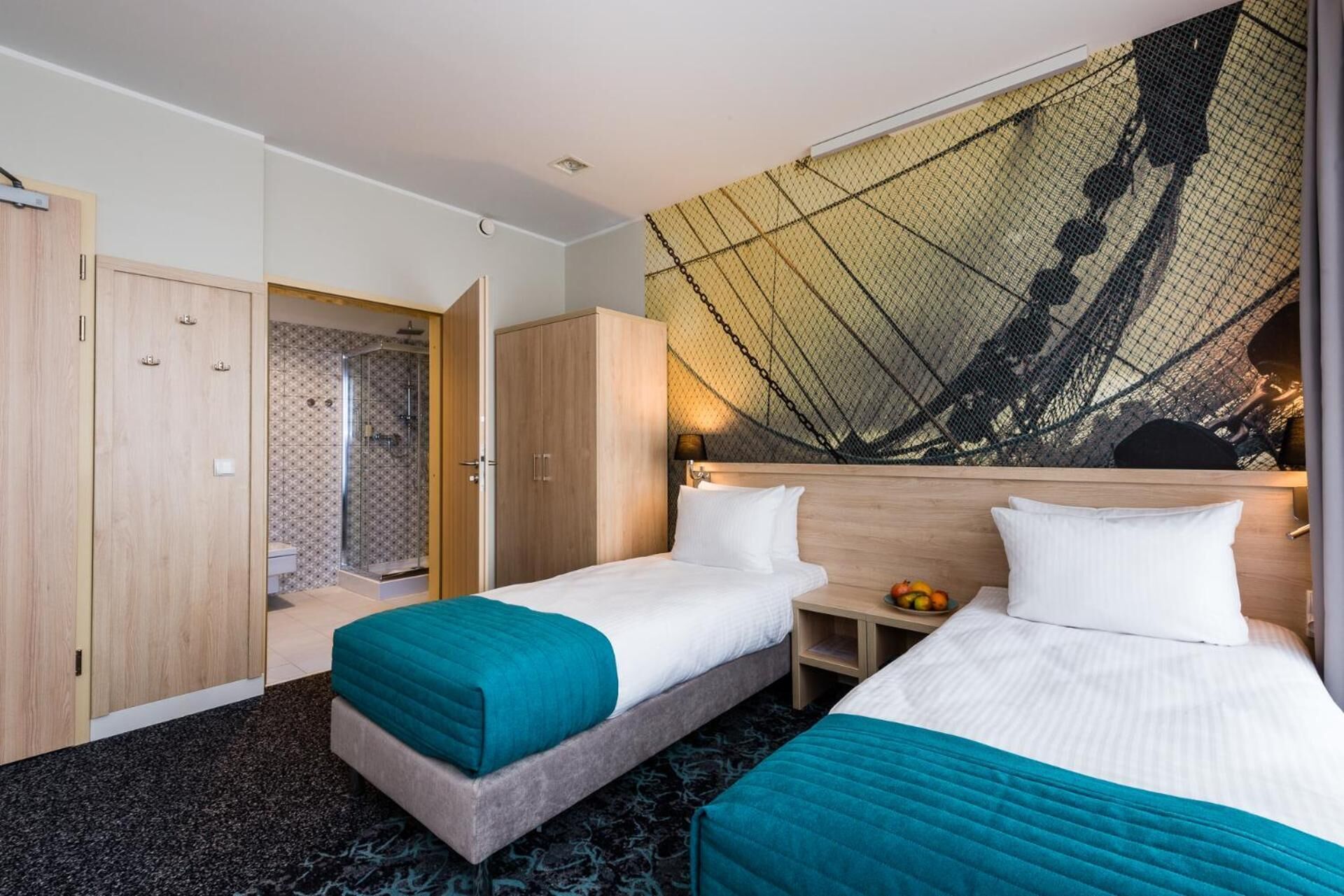 Habitación de hotel con dos camas, ducha y un ventanal con vistas a un puente.