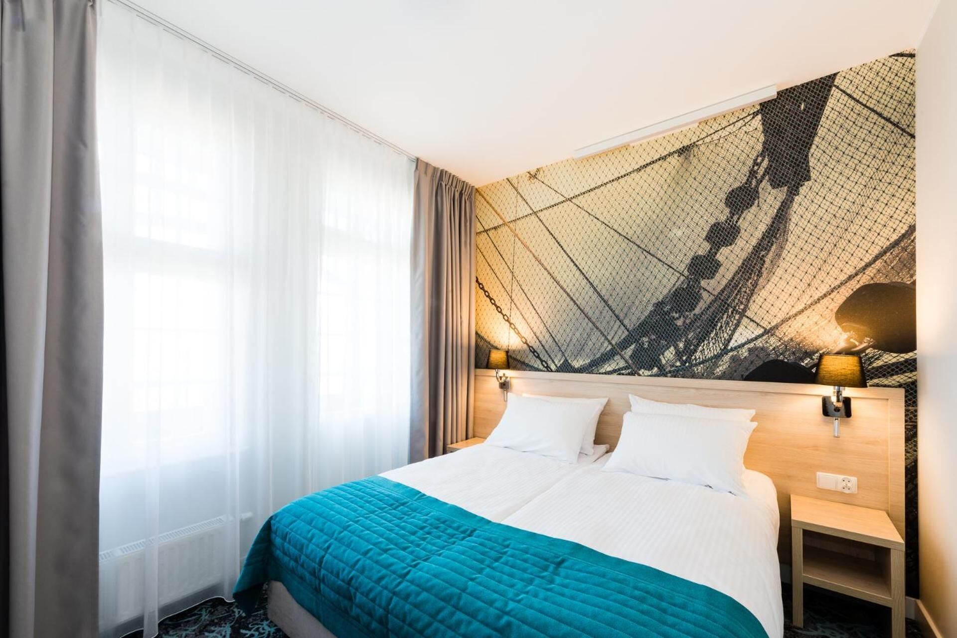 A hotel room with a bed, a nightstand, and a wall with a geometric pattern.
