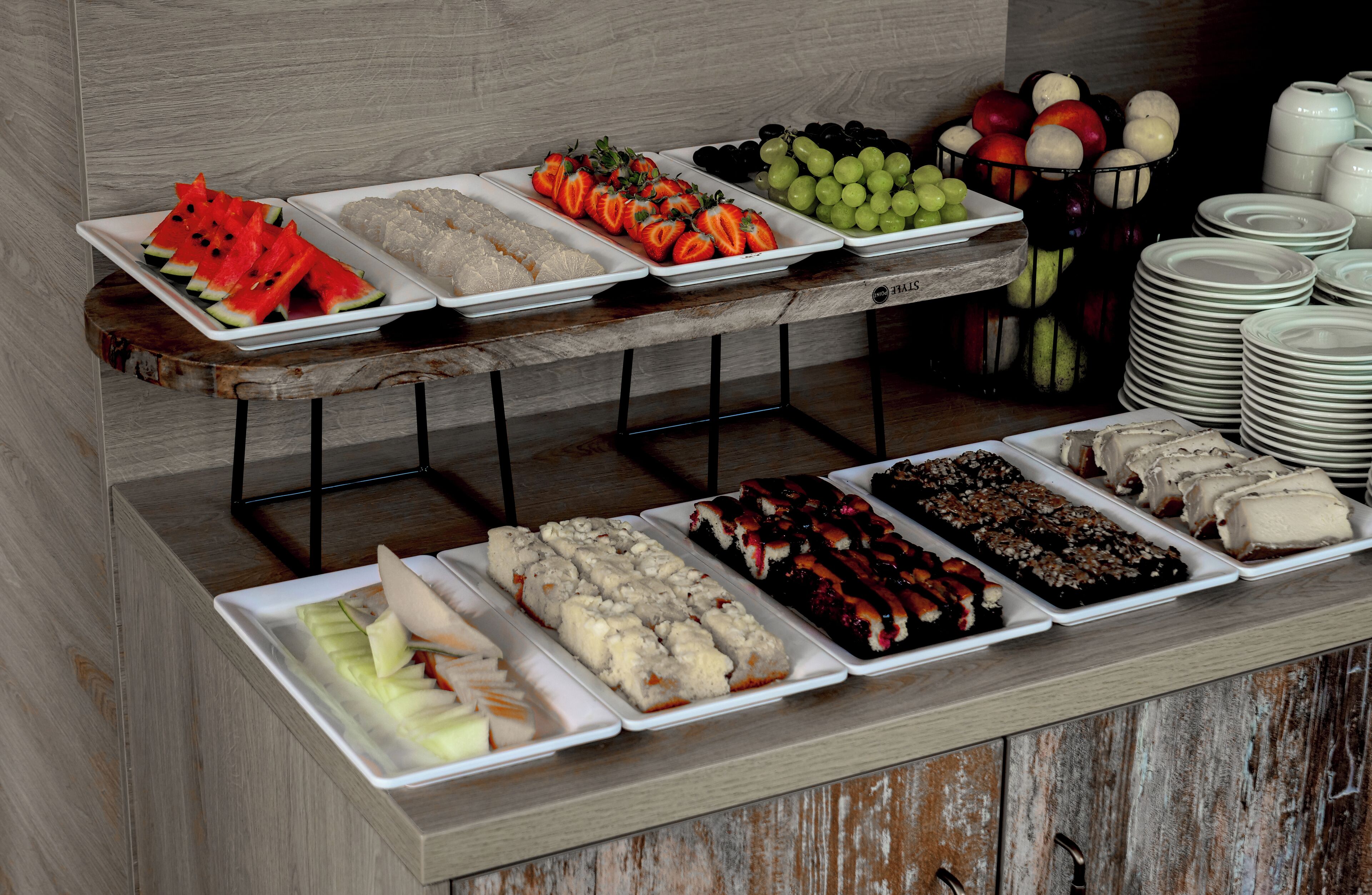 A buffet with various food items including fruits, desserts, and bread.