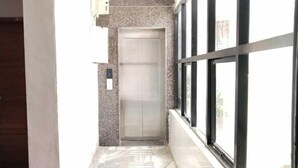 A narrow hallway with a tiled floor leading to an elevator.