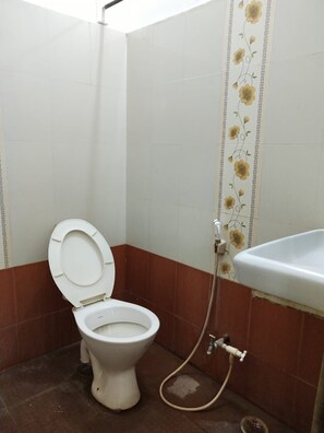 A bathroom with a toilet, a shower, and a sink. - iROOMZ Hotel Abhiman (Davanagere)
