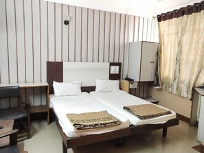 A hotel room with a large bed, two bedside tables, a desk, and a wardrobe. - iROOMZ Hotel Abhiman (Davanagere)