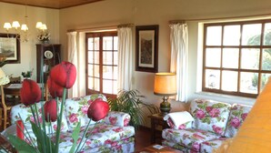 Ein gemütliches Wohnzimmer mit floralen Sofas, einer Tischlampe und einem Blumentopf.