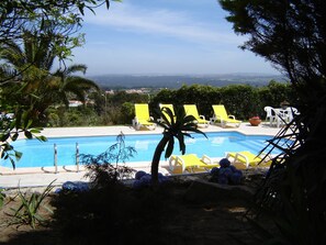 Ein Poolbereich mit gelben Liegestühlen und Blick auf die Stadt.